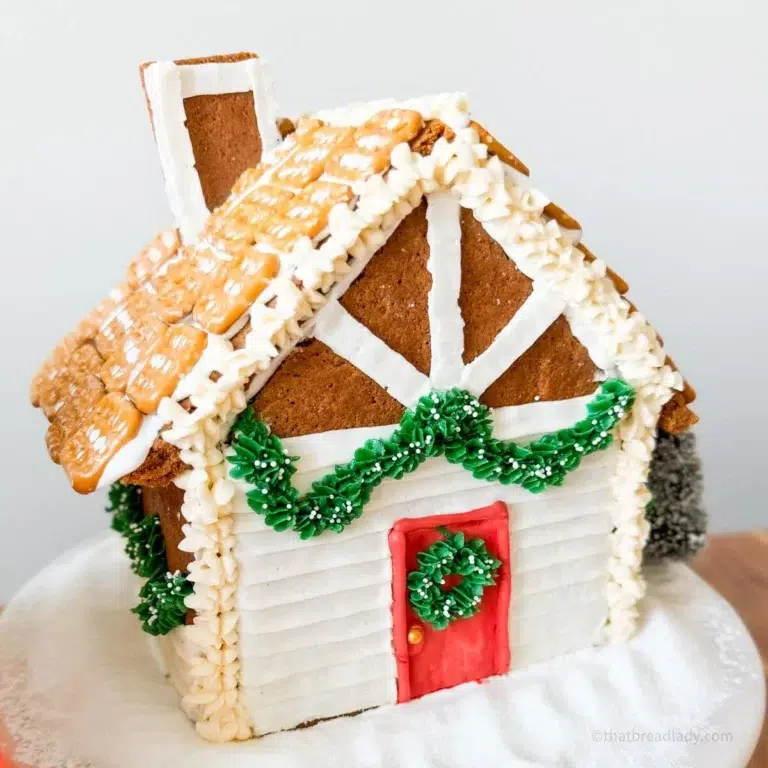 A gingerbread house made from my gingerbread house template printable, decorated with pretzels, royal icing garland and Crhistmas wreaths.