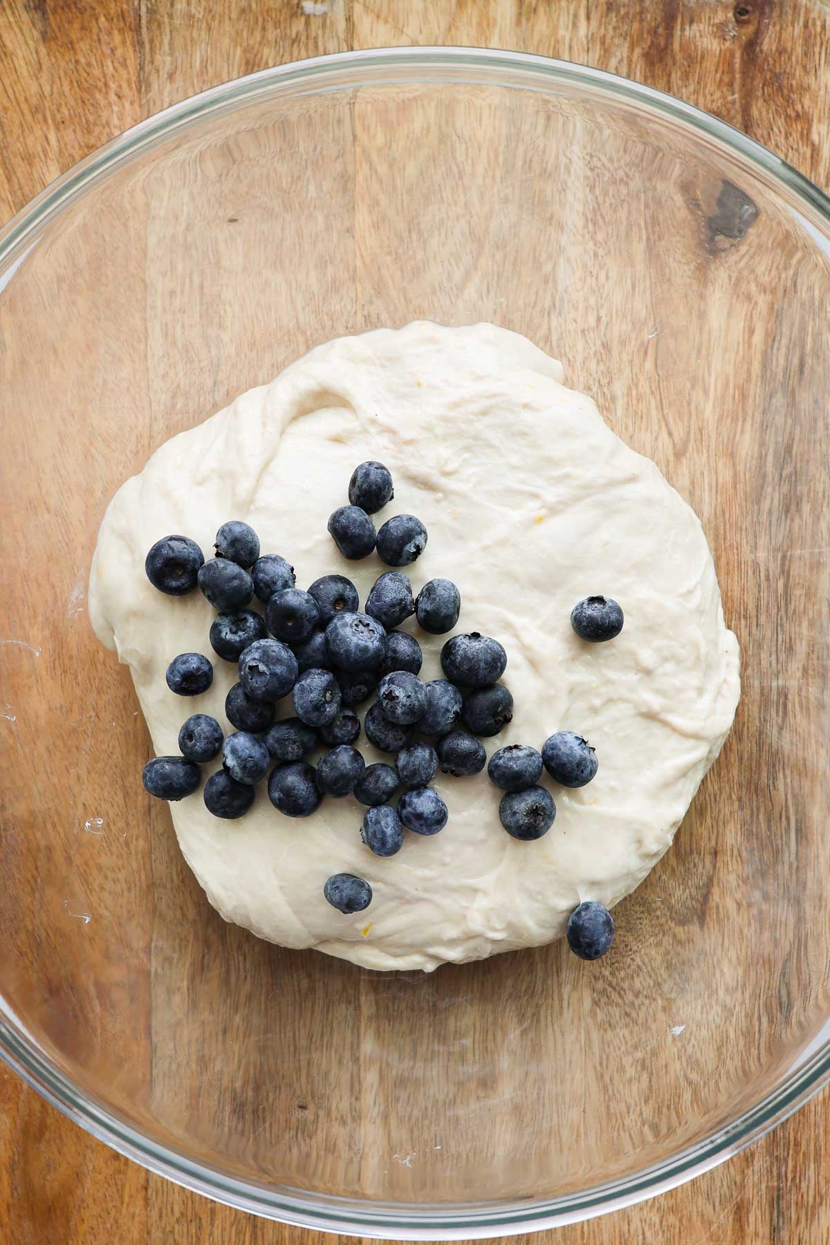 A glass bowl with sourdough and fresh blueberries on top of it.