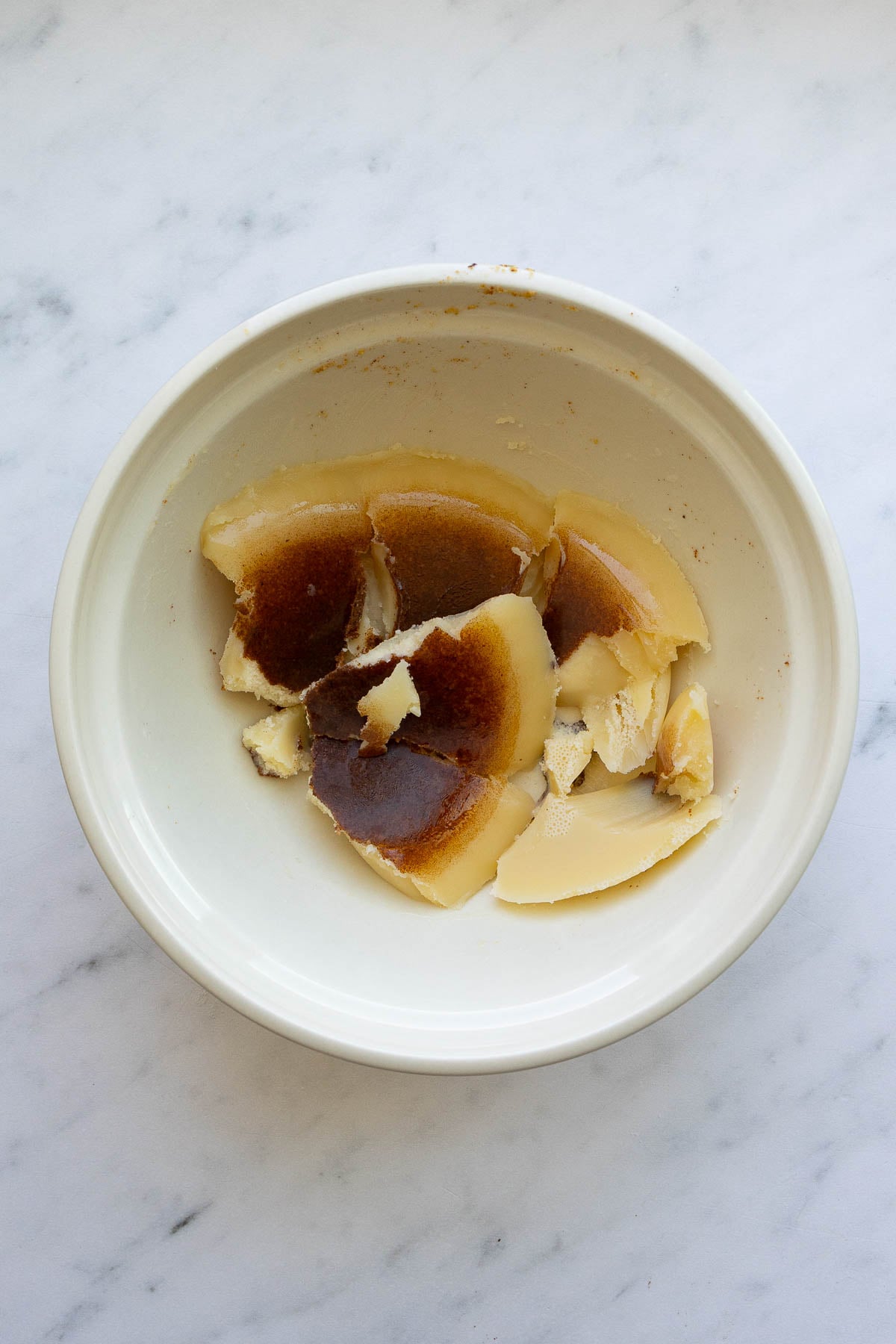 A bowl with browned butter in a solid form, broken into pieces.