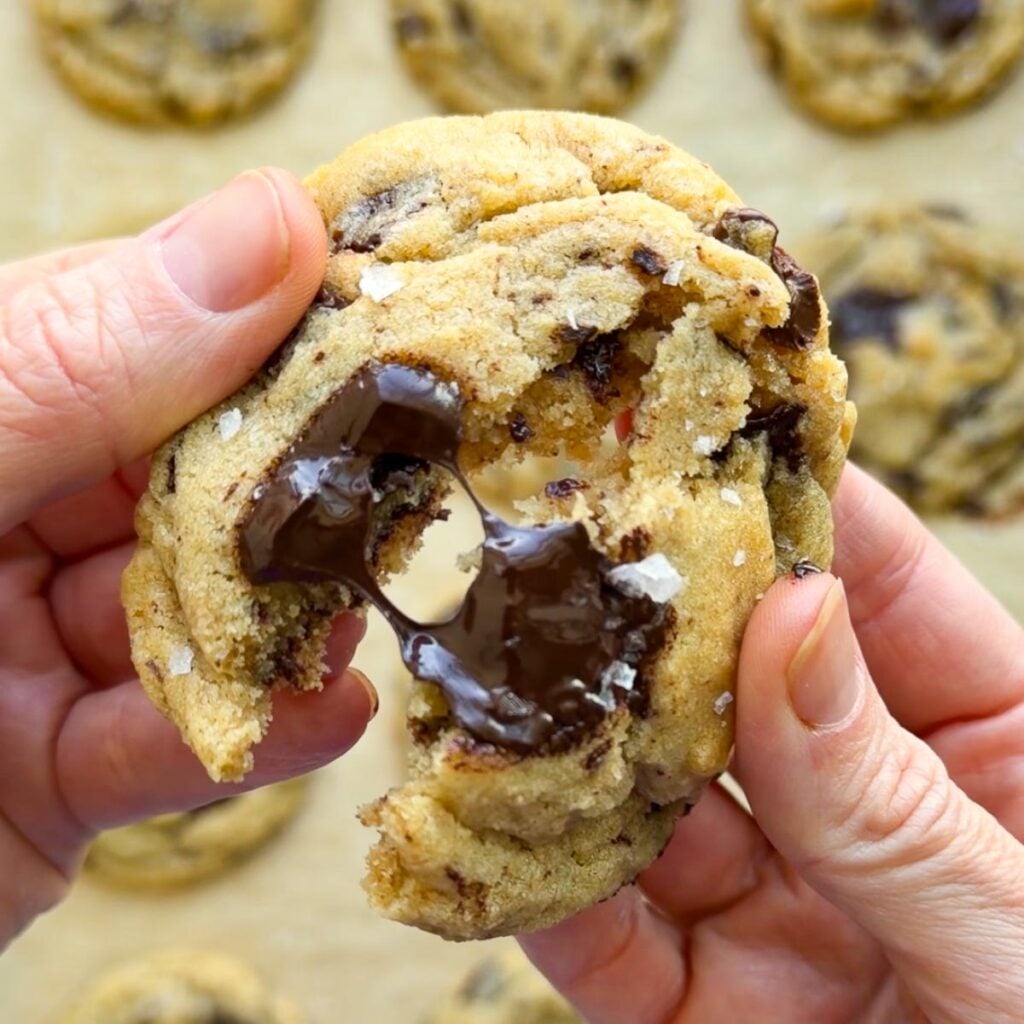Two hands break apart a Brown Butter Sourdough Chocolate Chip Cookie.