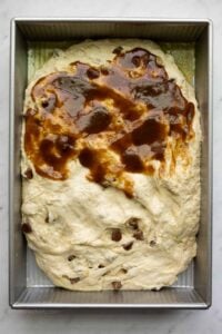 Chocolate chip banana bread focaccia in a 9x13-inch metal cake pan, with brown sugar cinnamon filling spread over half the dough.