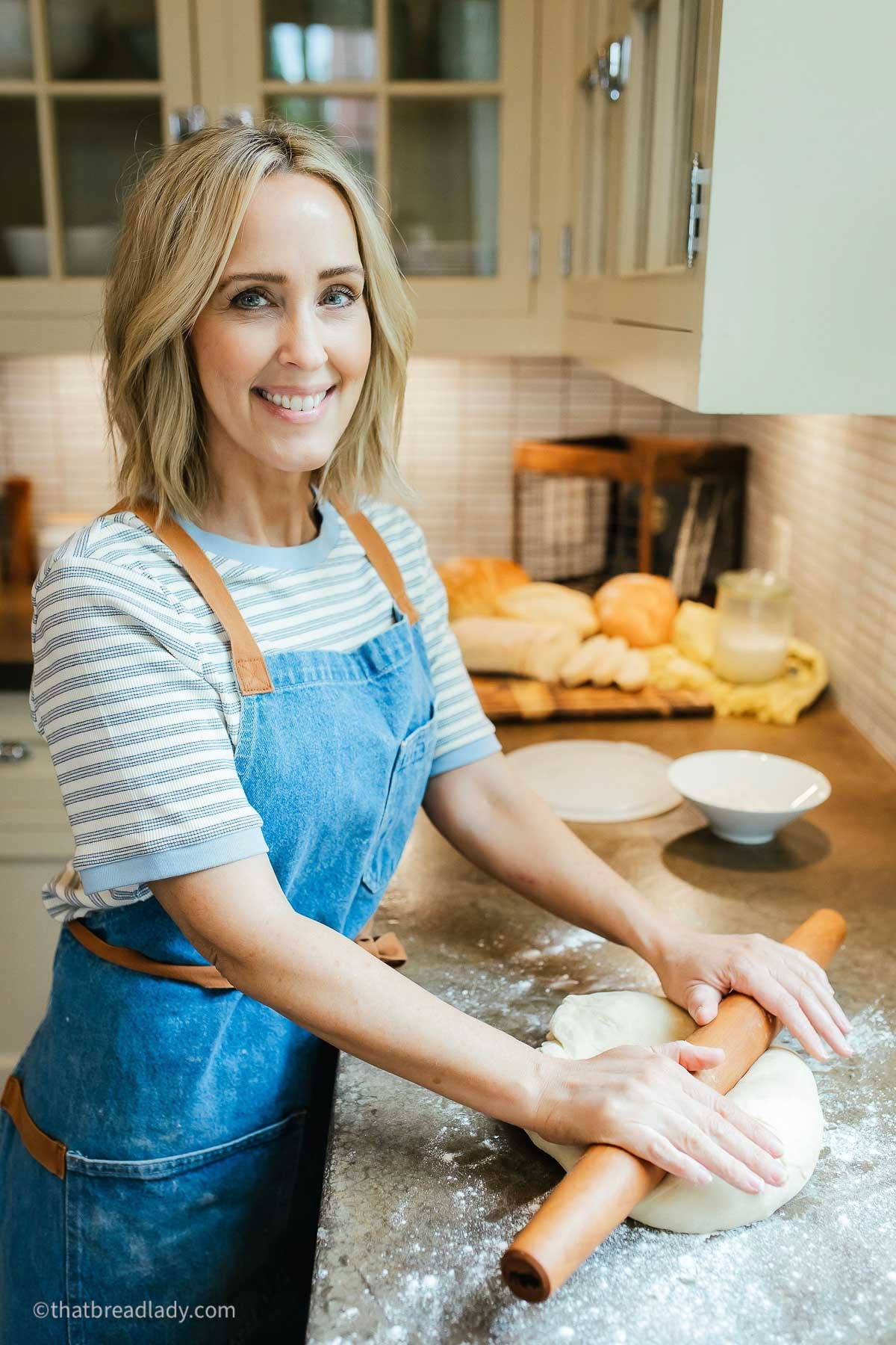 Heather Thomas, creator of That Bread Lady, standing at t a kitchen counter, rolling bread dough with a French rolling pin.