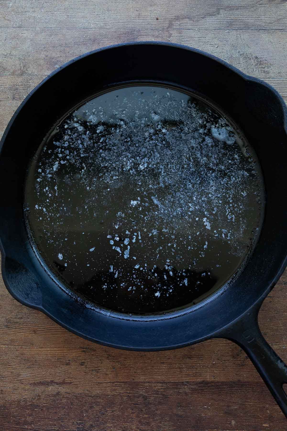 A cast iron pan with melted butter inside.