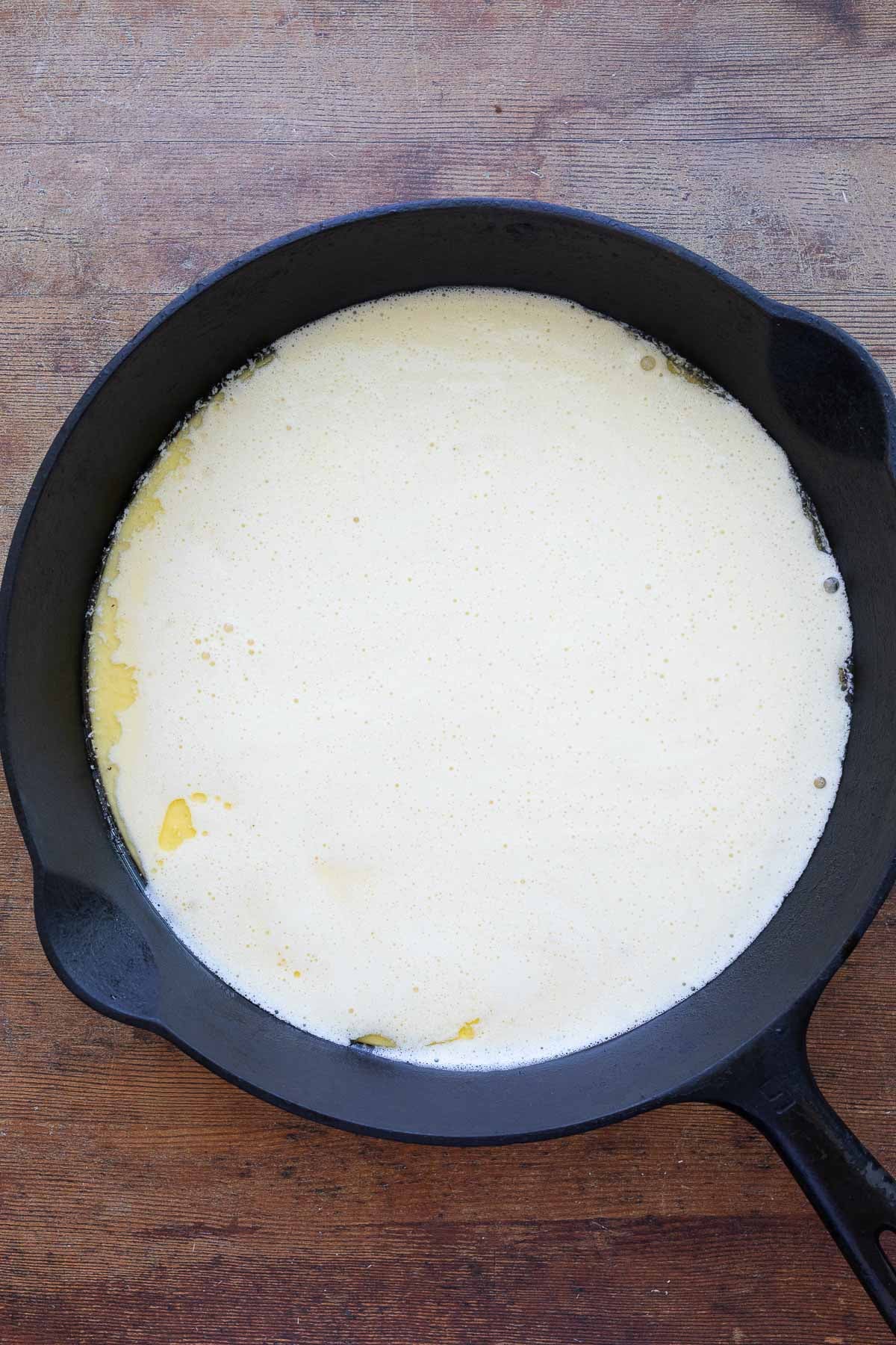 A cast iron pan with sourdough Dutch baby pancake batter inside.