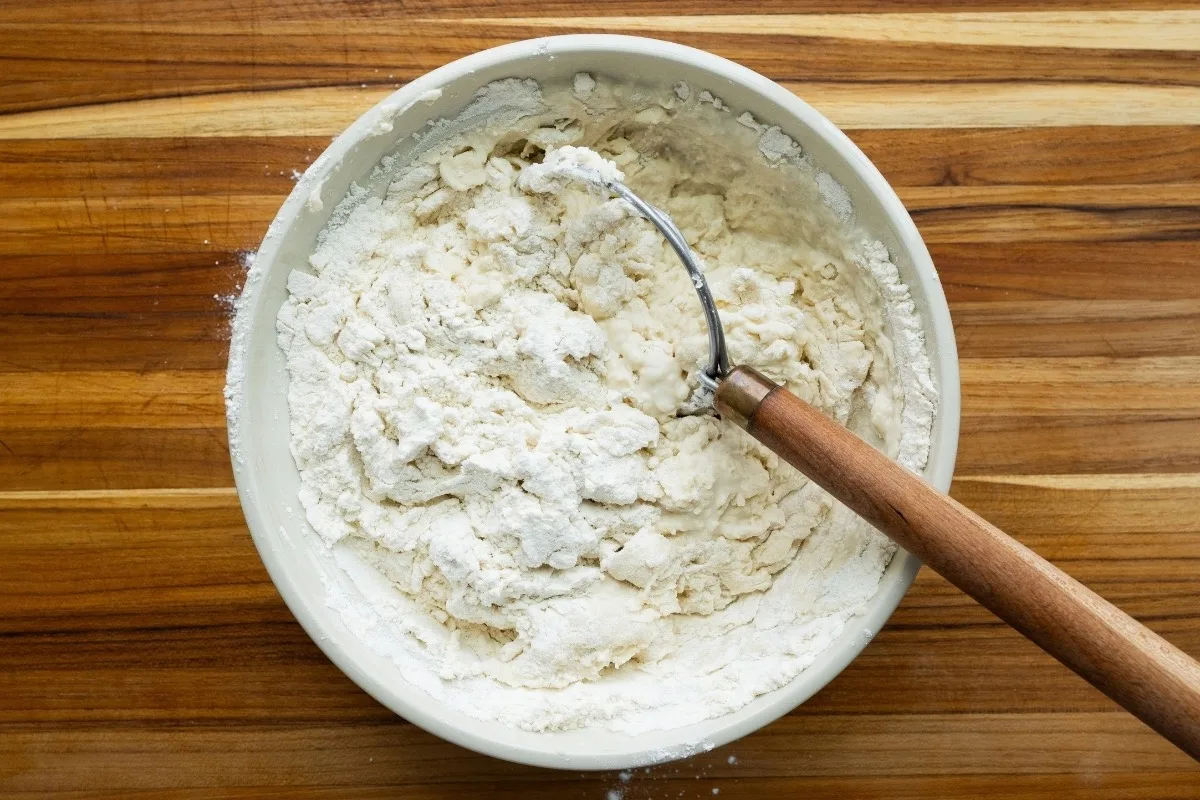 Flour, water, salt, and yeast, in a mixing bowl with a Danish whisk.