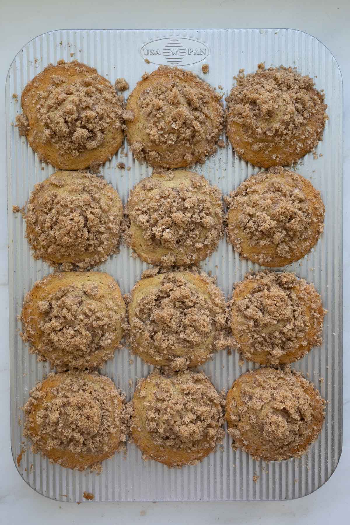 Baked sourdough coffee cake muffins with brown sugar crumb topping, in a metal muffin tin.