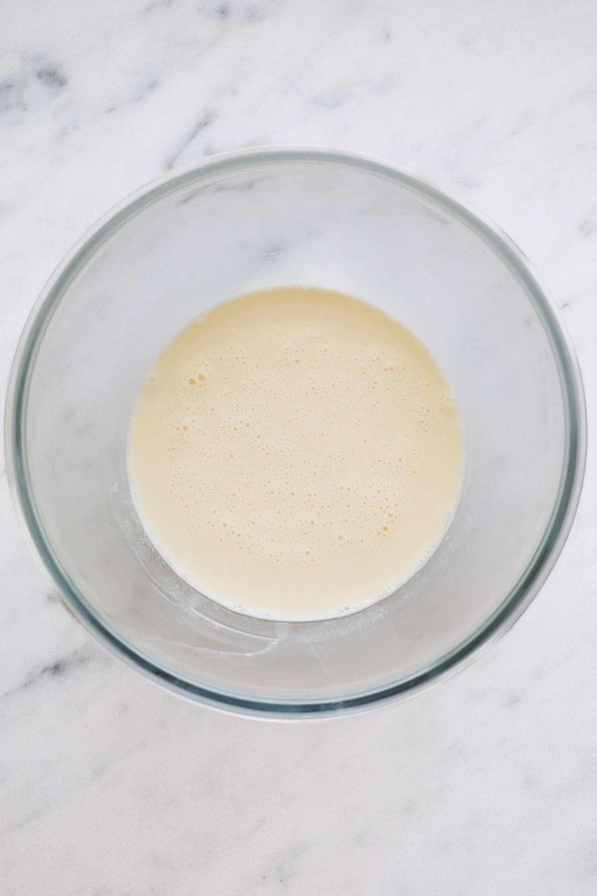 A glass bowl with the wet ingredients for sourdough coffee cake muffins all mixed together.